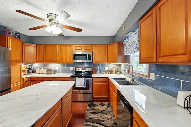 kitchen featuring brown cabinetry, stainless steel appliances, a textured ceiling, and a sink