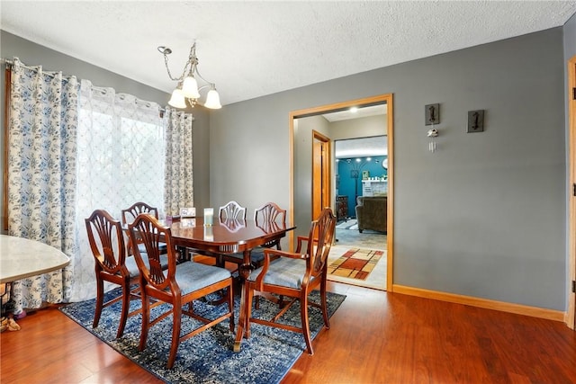dining space with baseboards, a chandelier, and wood finished floors