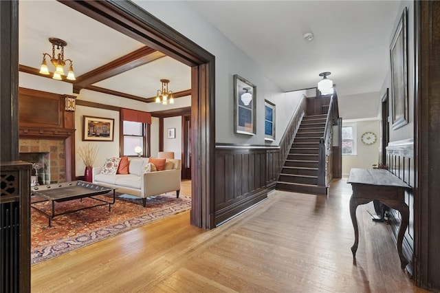 5818 Aylesboro Ave, Squirrel Hill, PA 15217 - stairs featuring wood finished floors, a fireplace, a wainscoted wall, and a chandelier