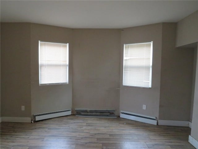unfurnished room featuring wood finished floors, a baseboard radiator, baseboards, and a baseboard heating unit