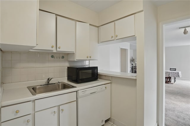 kitchen with light countertops, a sink, decorative backsplash, black microwave, and dishwasher