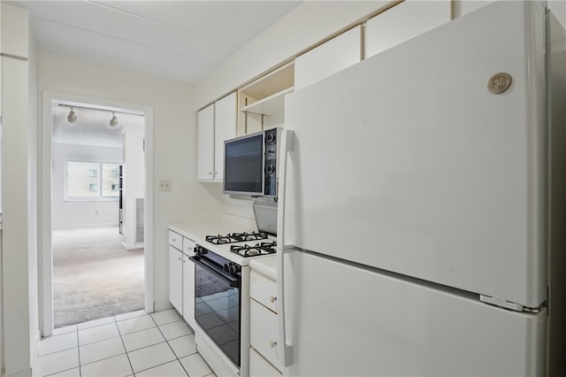 kitchen with white cabinets, stainless steel microwave, freestanding refrigerator, gas range oven, and light countertops