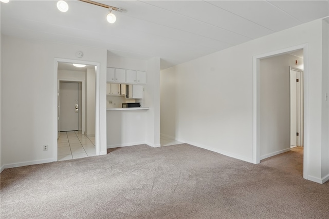unfurnished living room with light carpet and baseboards