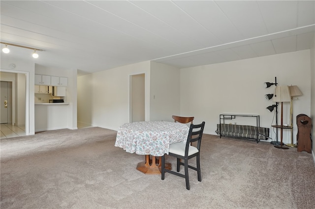 dining space featuring rail lighting and light colored carpet