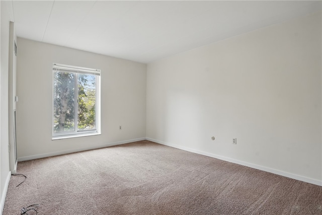 spare room featuring carpet floors and baseboards