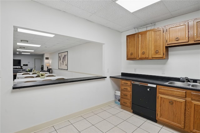 kitchen featuring brown cabinets, dark countertops, dishwasher, a sink, and a paneled ceiling