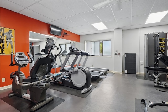 workout area featuring baseboards and a drop ceiling