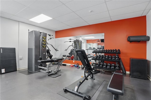 exercise room with baseboards and a drop ceiling