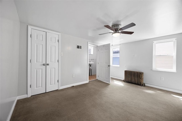 unfurnished bedroom with radiator heating unit, visible vents, carpet flooring, and baseboards