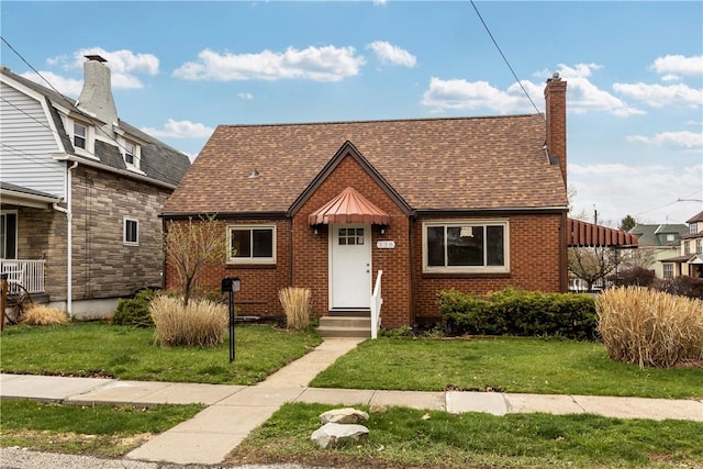 138 W Larkspur St, Munhall, PA 15120 - view of front of home featuring brick siding, roof with shingles, a chimney, and a front lawn