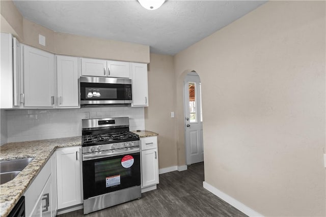 138 W Larkspur St, Munhall, PA 15120 - kitchen featuring tasteful backsplash, arched walkways, stainless steel appliances, baseboards, and dark wood-style floors