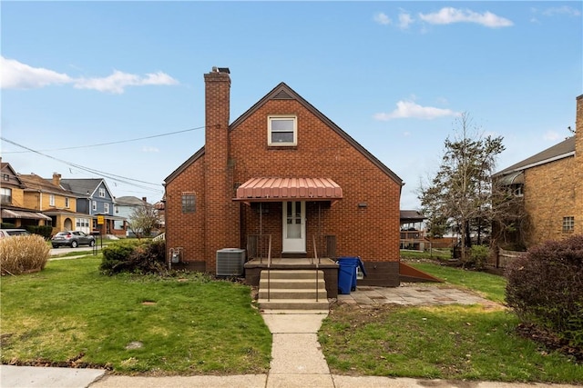 138 W Larkspur St, Munhall, PA 15120 - view of front facade with a chimney, cooling unit, a front yard, brick siding, and a residential view