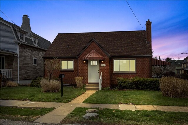138 W Larkspur St, Munhall, PA 15120 - view of front of home featuring brick siding, a shingled roof, a front yard, and a chimney