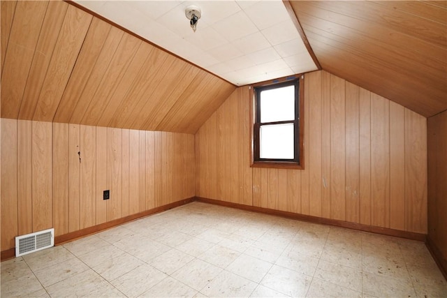 additional living space with light floors, wooden walls, lofted ceiling, and visible vents