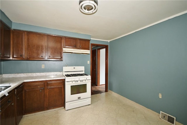 kitchen featuring visible vents, white range with gas stovetop, light countertops, under cabinet range hood, and ornamental molding