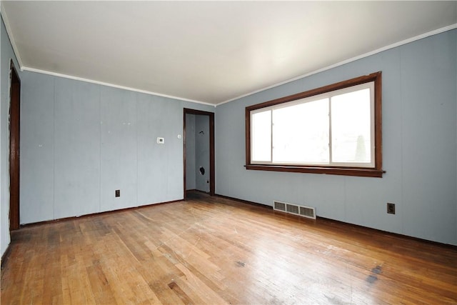 unfurnished room featuring light wood-style floors, visible vents, and crown molding