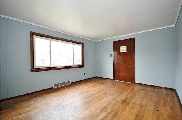 unfurnished room featuring plenty of natural light, visible vents, crown molding, and hardwood / wood-style floors