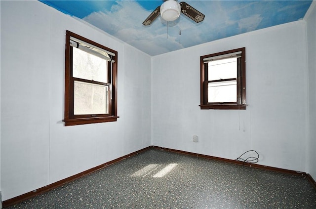 spare room with plenty of natural light, a ceiling fan, and baseboards