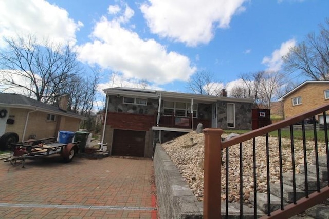 exterior space with an attached garage, a chimney, and decorative driveway