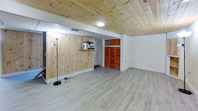 finished below grade area featuring wood finished floors, visible vents, wood walls, and baseboards