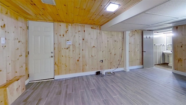 interior space with wood ceiling, wood walls, wood finished floors, and baseboards