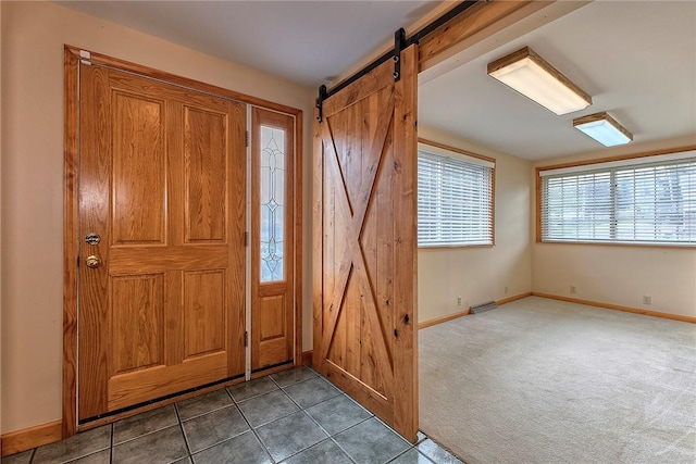 tiled foyer entrance with baseboards, carpet, a barn door, and visible vents