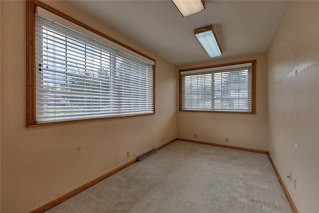 spare room featuring carpet floors, a wealth of natural light, baseboards, and visible vents