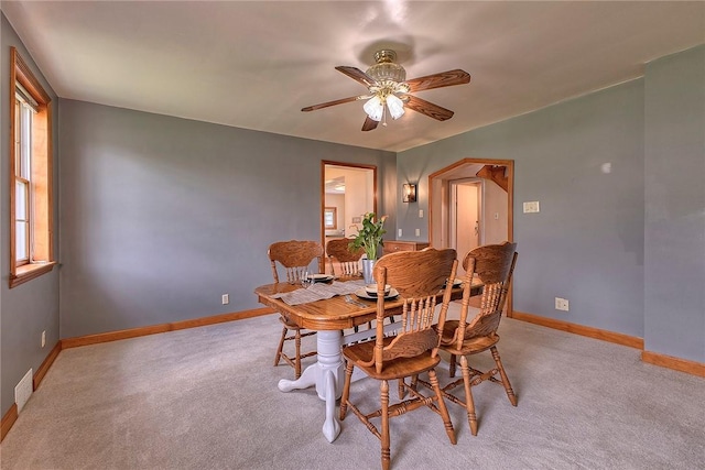 dining room featuring a ceiling fan, baseboards, visible vents, and light carpet