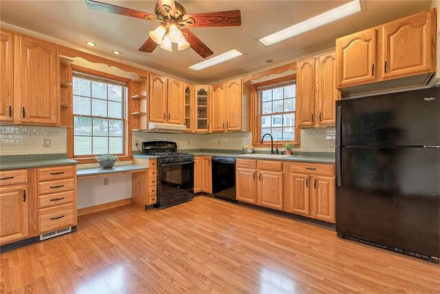 kitchen featuring open shelves, a sink, light wood-type flooring, under cabinet range hood, and black appliances