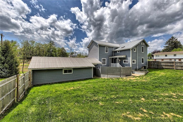 back of house with a fenced backyard, a lawn, and metal roof