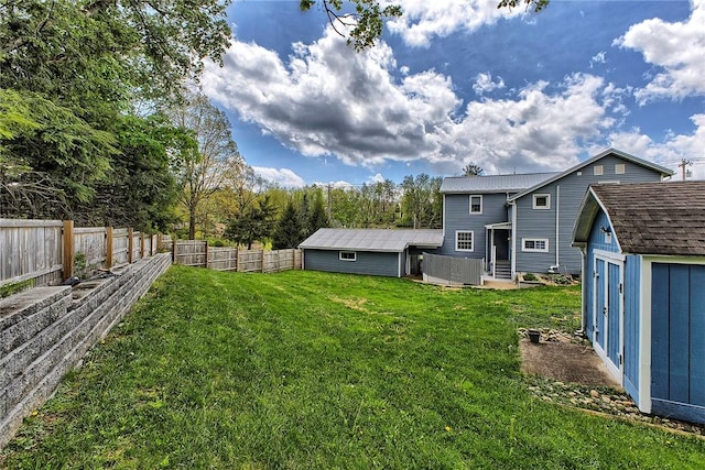 view of yard with a fenced backyard, a shed, and an outbuilding