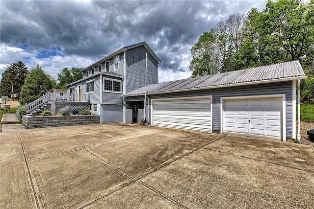 view of side of property with concrete driveway, an attached garage, and metal roof