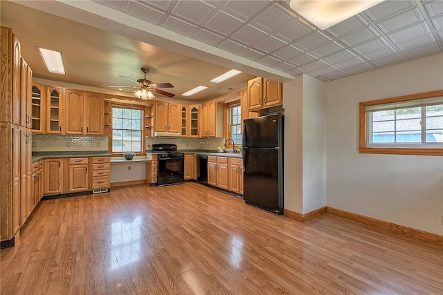kitchen with baseboards, a sink, a healthy amount of sunlight, and black appliances