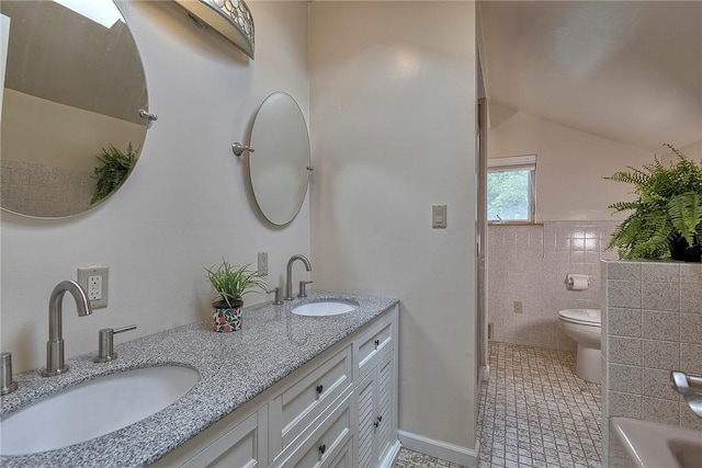 bathroom featuring double vanity, toilet, vaulted ceiling, and a sink