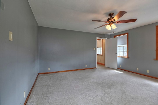empty room with baseboards, ceiling fan, and carpet
