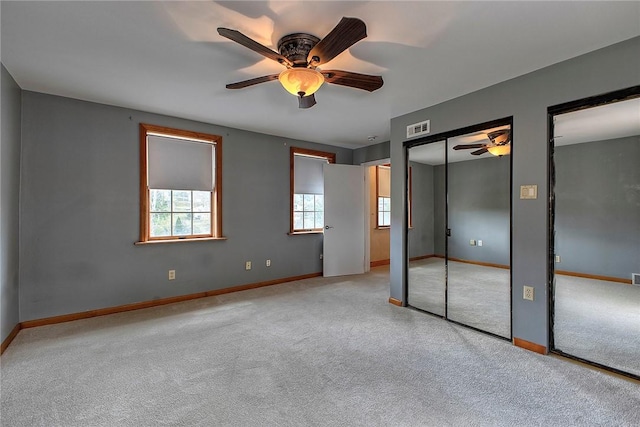 unfurnished bedroom featuring visible vents, two closets, baseboards, a ceiling fan, and carpet