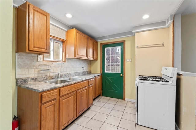 2006 Locust St, Swissvale, PA 15218 - kitchen with white range with gas stovetop, a sink, washer / dryer, light tile patterned floors, and decorative backsplash