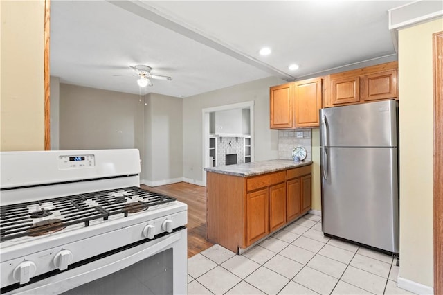 2006 Locust St, Swissvale, PA 15218 - kitchen with freestanding refrigerator, white range with gas stovetop, a peninsula, ceiling fan, and baseboards