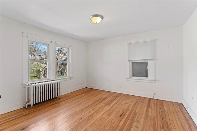 empty room with light wood finished floors, radiator heating unit, and baseboards