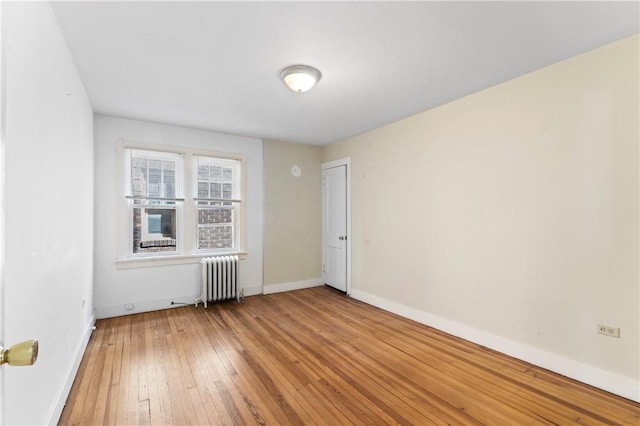 unfurnished room with radiator, light wood finished floors, and baseboards