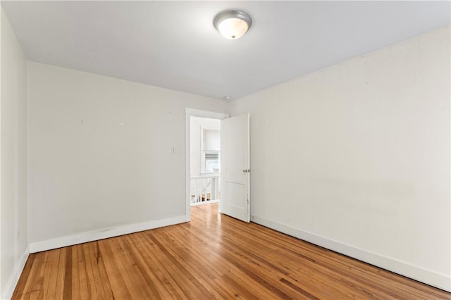unfurnished room with hardwood / wood-style floors and baseboards