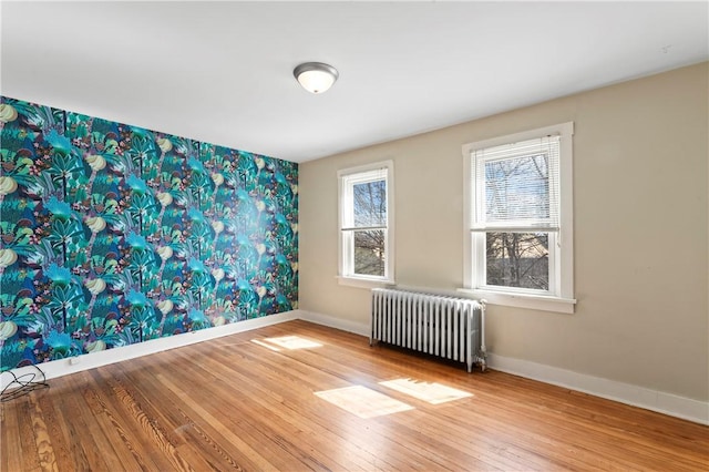 2006 Locust St, Swissvale, PA 15218 - empty room with radiator heating unit, baseboards, hardwood / wood-style floors, wallpapered walls, and an accent wall