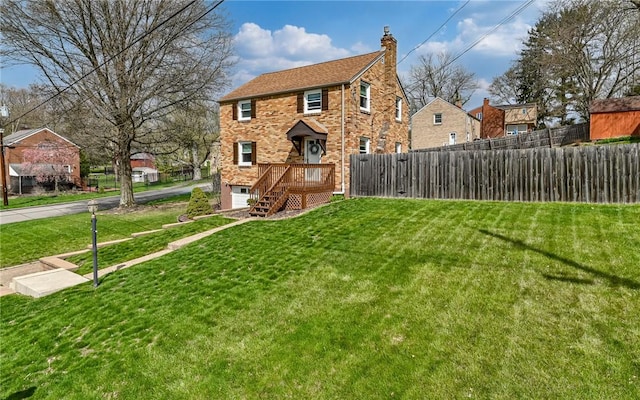 exterior space featuring a front yard, driveway, a chimney, and fence