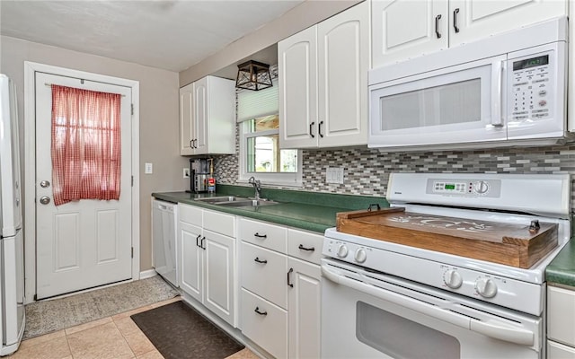 kitchen featuring a sink, tasteful backsplash, dark countertops, white cabinetry, and white appliances