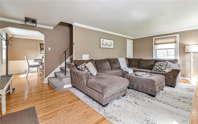 living area with light wood-type flooring, arched walkways, stairway, and crown molding