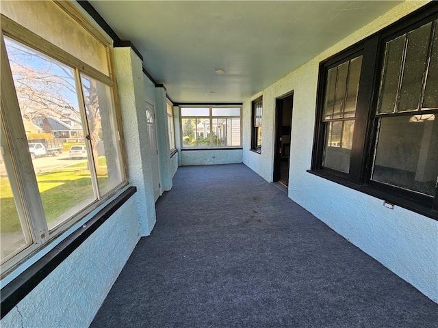 unfurnished sunroom with a textured wall and carpet flooring
