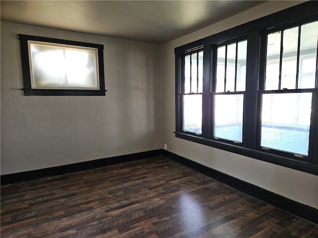 unfurnished room with dark wood finished floors, baseboards, and a healthy amount of sunlight