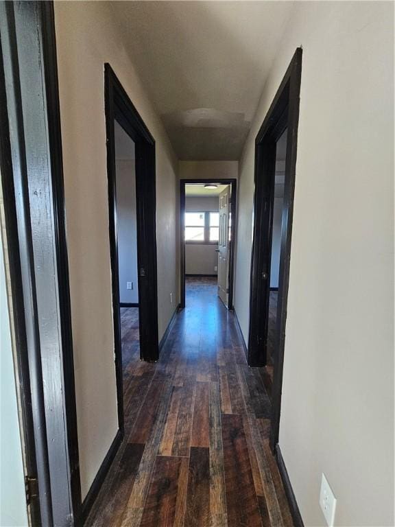 corridor with baseboards and dark wood finished floors