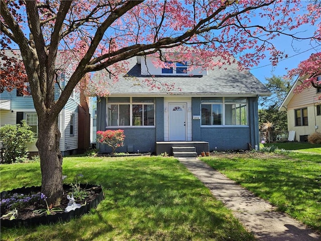 view of front of house with roof with shingles and a front yard