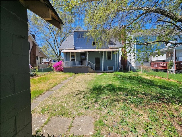 rear view of property featuring covered porch, a yard, and a fenced backyard
